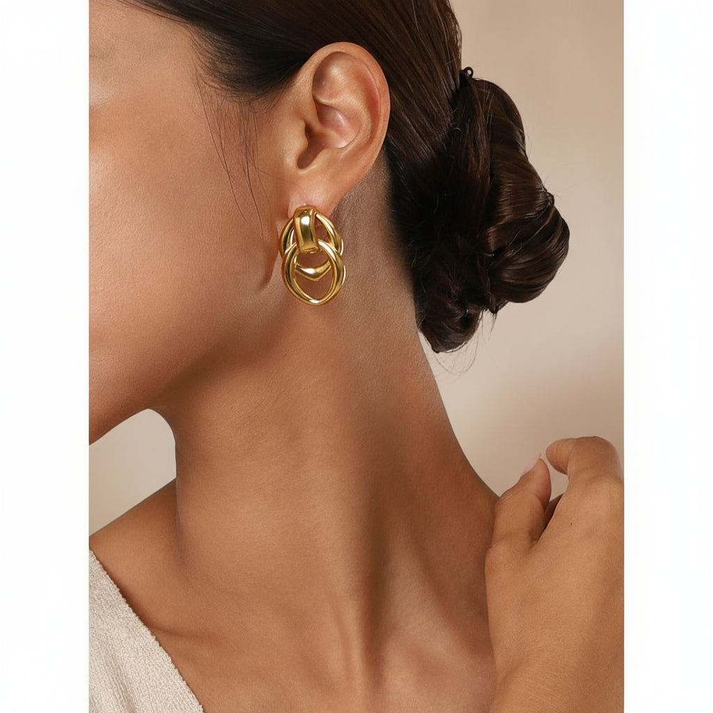Gold hoop earrings worn by a person with a neutral background