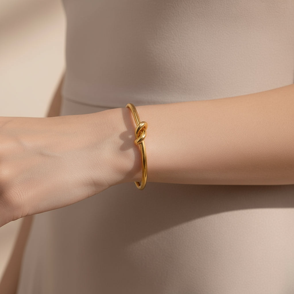 Gold bracelet on a person's wrist against a neutral background