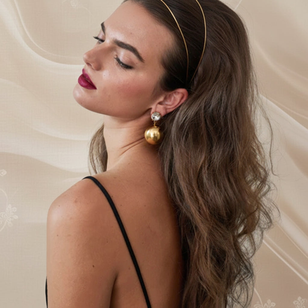 Woman wearing gold earrings with a neutral background