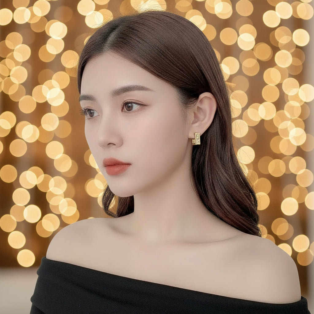 Close-up of a person wearing a gold earring with a neutral background