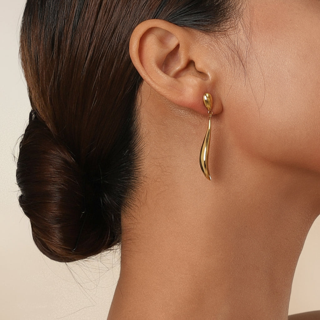 Gold earring worn by a person with a neutral background