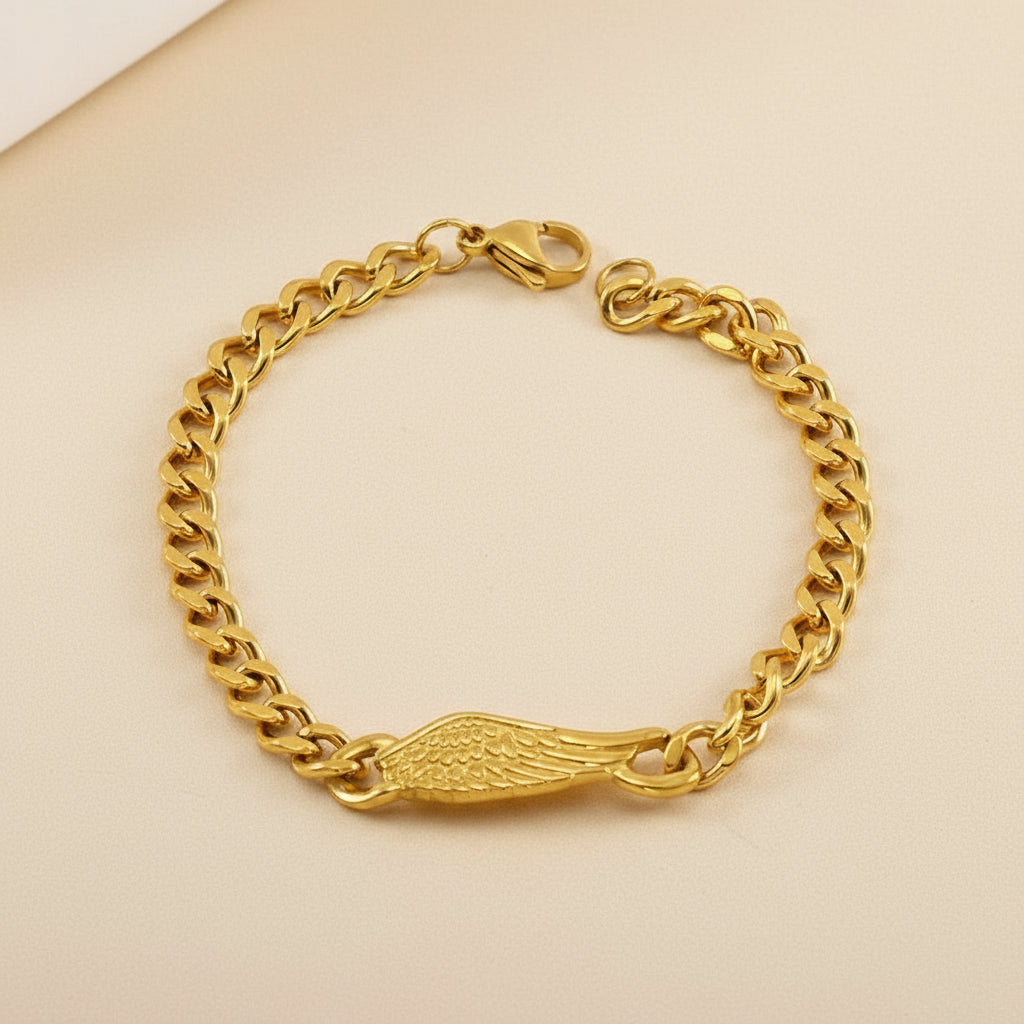Gold chain bracelet with a wing charm on a beige background