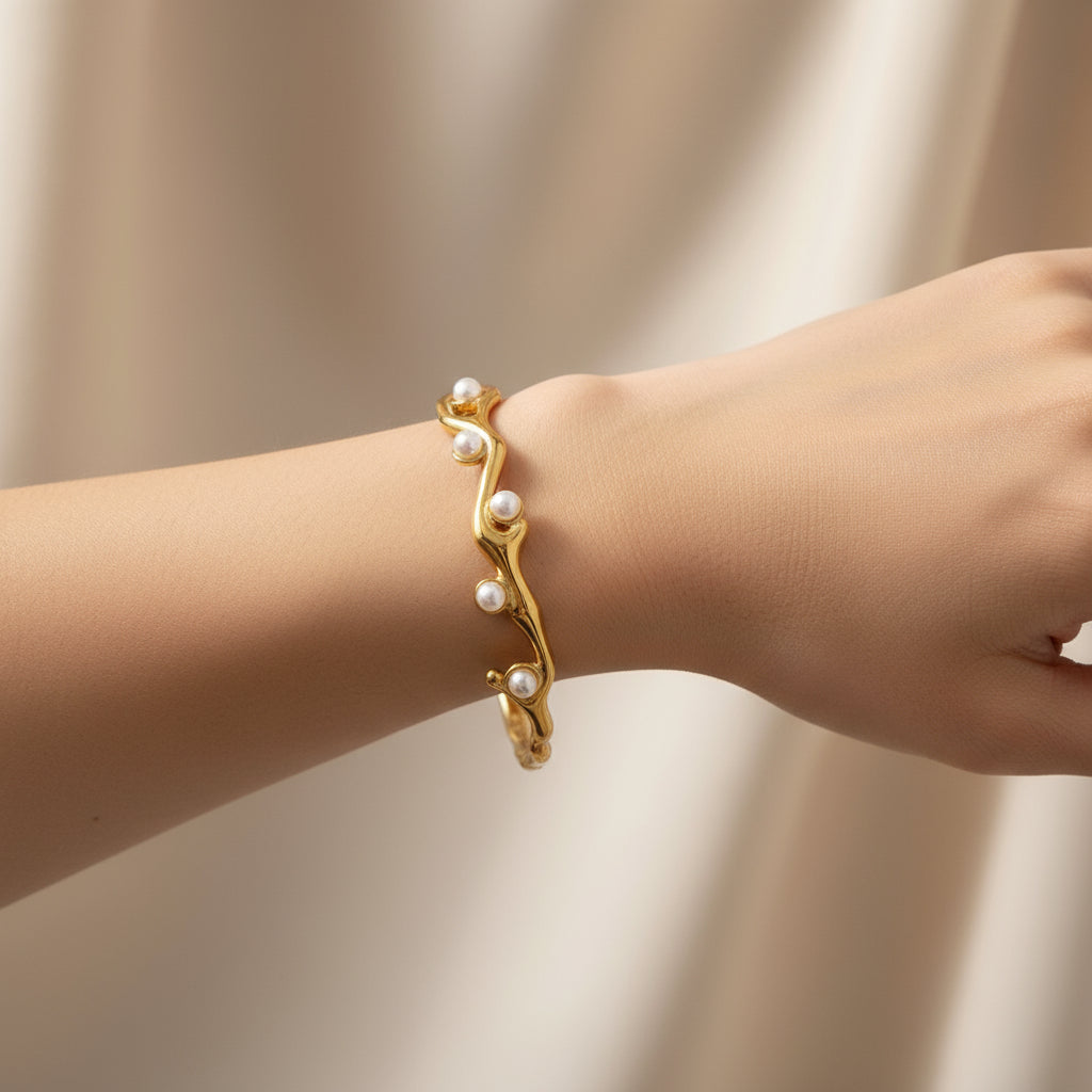 Gold bracelet with pearls and measurements on a white background